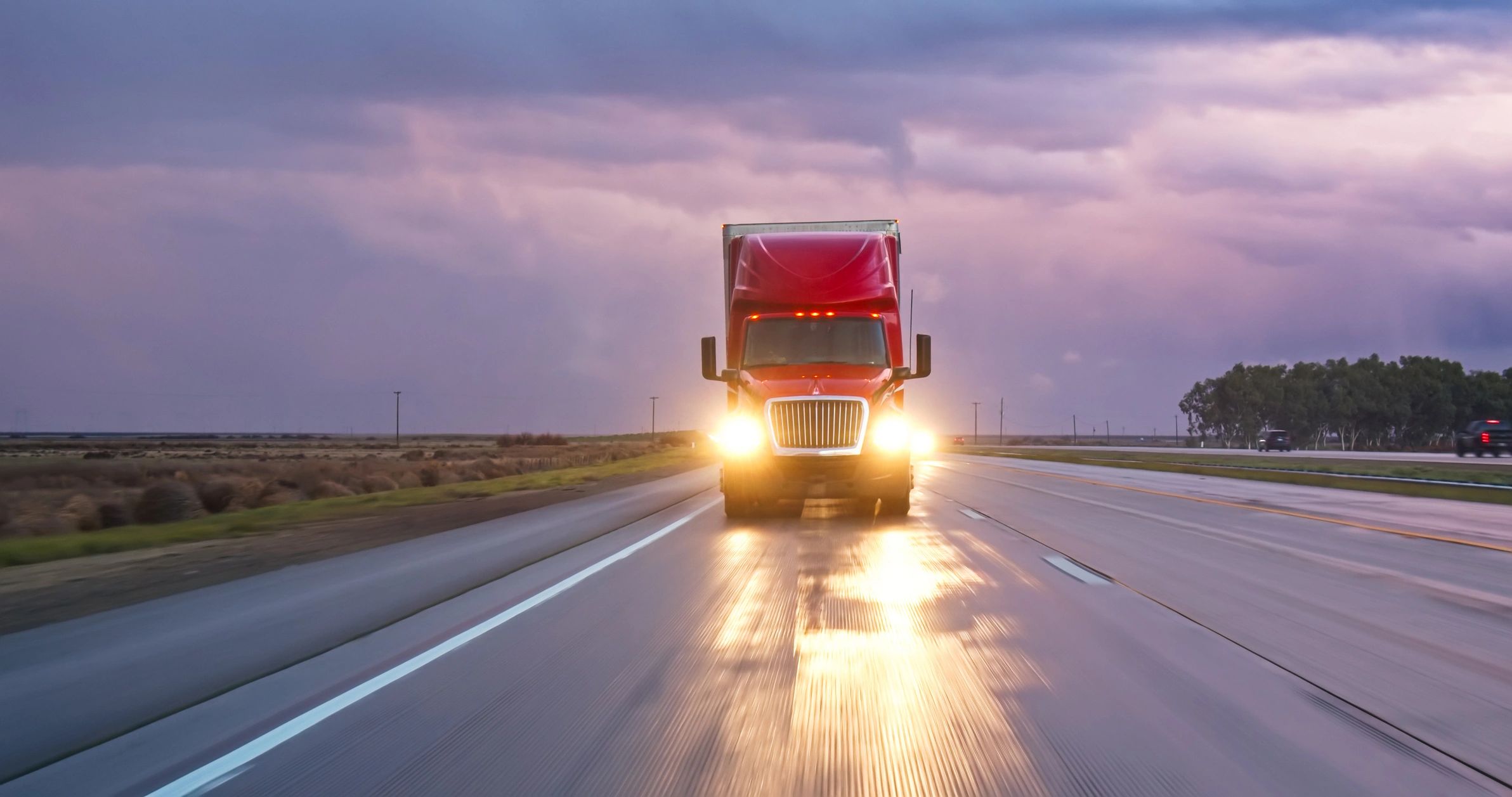 Semi-truck driving on an interstate at sunset